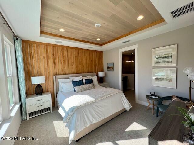 bedroom featuring light colored carpet, a raised ceiling, wood walls, and wooden ceiling