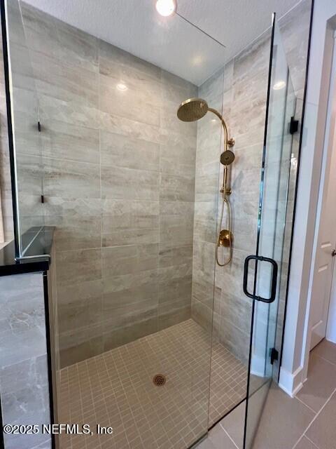 bathroom with tile patterned flooring, a shower with door, and a textured ceiling