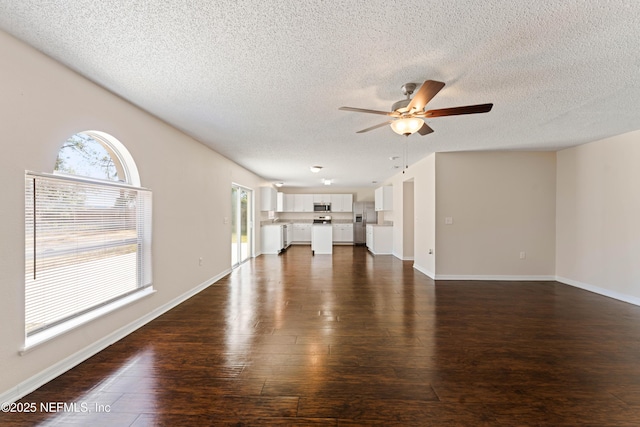 unfurnished living room with ceiling fan, plenty of natural light, dark hardwood / wood-style floors, and a textured ceiling