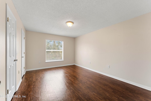 unfurnished room featuring dark hardwood / wood-style flooring and a textured ceiling