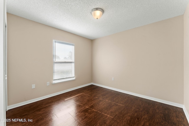 empty room with dark hardwood / wood-style floors and a textured ceiling