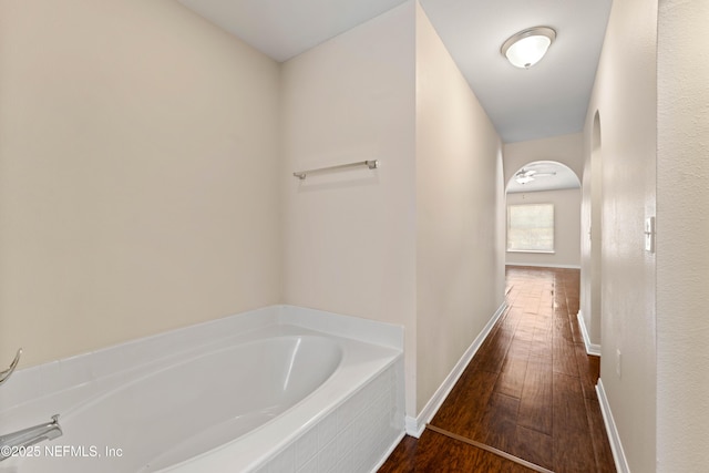 bathroom featuring wood-type flooring and a relaxing tiled tub