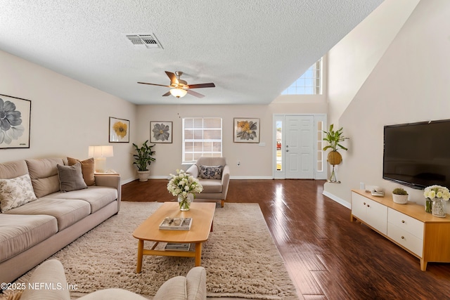 living room with dark hardwood / wood-style flooring, ceiling fan, and a textured ceiling