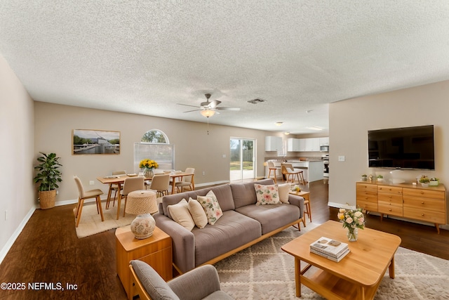 living room with ceiling fan, dark wood-type flooring, and a textured ceiling