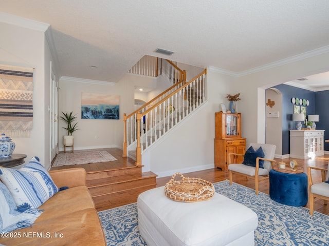 living room with hardwood / wood-style flooring, ornamental molding, and a textured ceiling