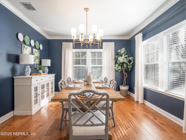 dining area with crown molding, hardwood / wood-style floors, a notable chandelier, and a textured ceiling