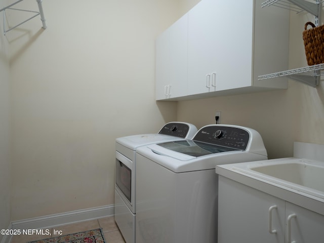 laundry room featuring light tile patterned floors, washer and clothes dryer, and cabinets