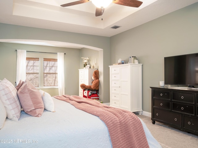 carpeted bedroom featuring a raised ceiling and ceiling fan