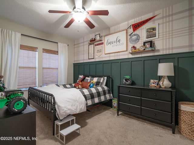 bedroom featuring ceiling fan, light colored carpet, and a textured ceiling