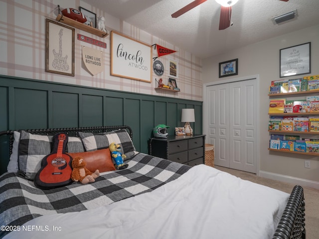 carpeted bedroom with ceiling fan, a closet, and a textured ceiling