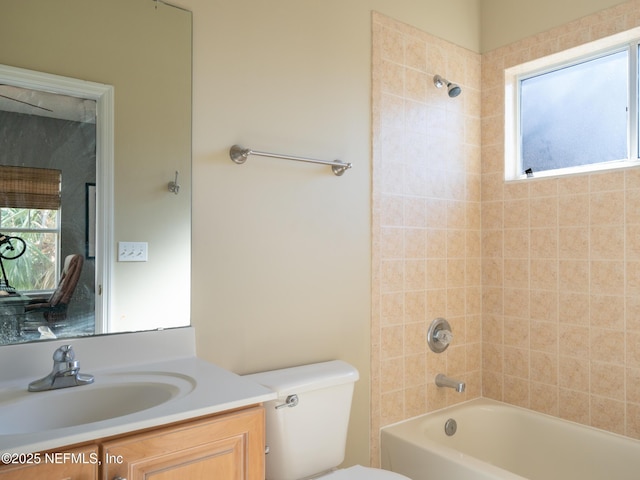 full bathroom featuring tiled shower / bath, vanity, and toilet