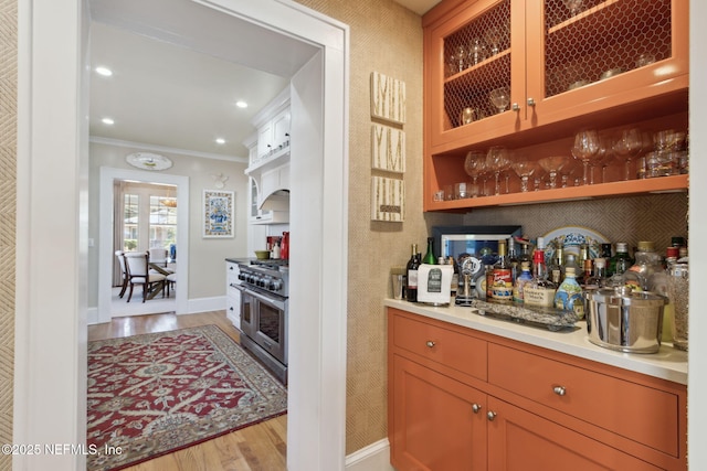 bar featuring crown molding, double oven range, and light hardwood / wood-style floors