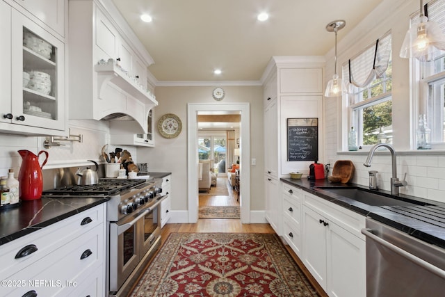 kitchen with pendant lighting, sink, light hardwood / wood-style flooring, appliances with stainless steel finishes, and white cabinets