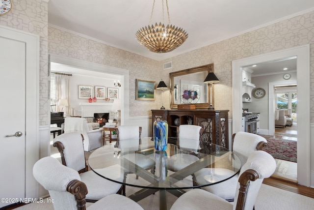 dining area featuring crown molding, wood-type flooring, and an inviting chandelier