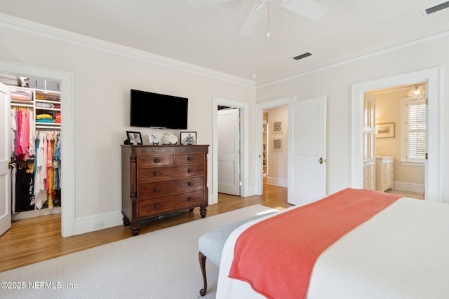 bedroom featuring ensuite bathroom, ornamental molding, light hardwood / wood-style floors, a walk in closet, and a closet