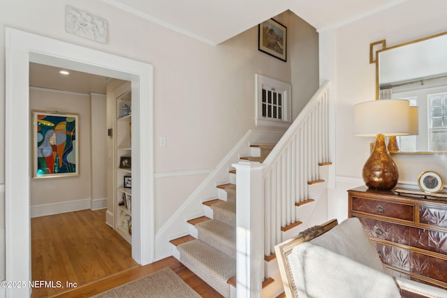 stairs featuring ornamental molding and hardwood / wood-style floors