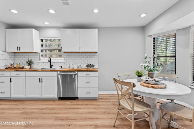 kitchen featuring stainless steel dishwasher, wooden counters, sink, and white cabinets