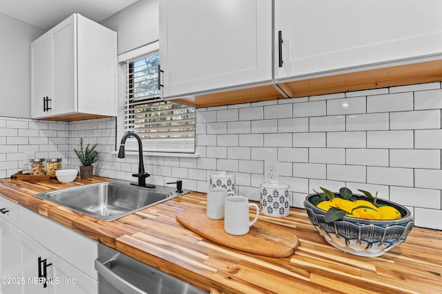 kitchen featuring dishwasher, white cabinetry, sink, wooden counters, and decorative backsplash