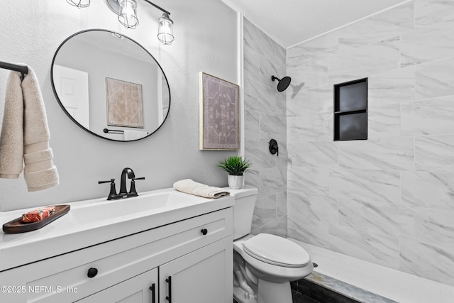 bathroom with vanity, a tile shower, and toilet