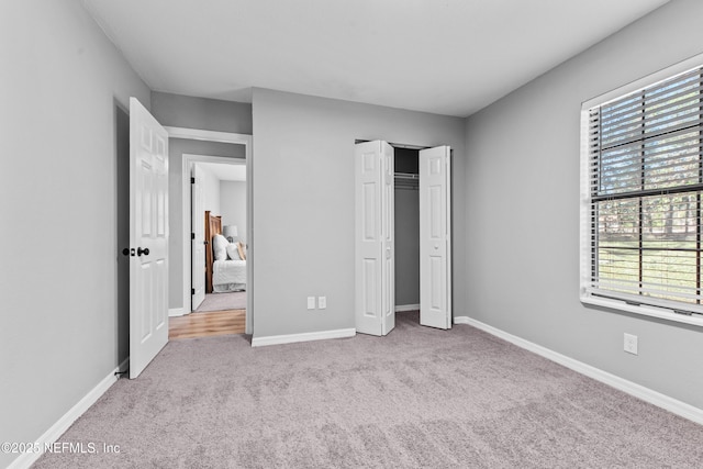 unfurnished bedroom with multiple windows, a closet, and light carpet