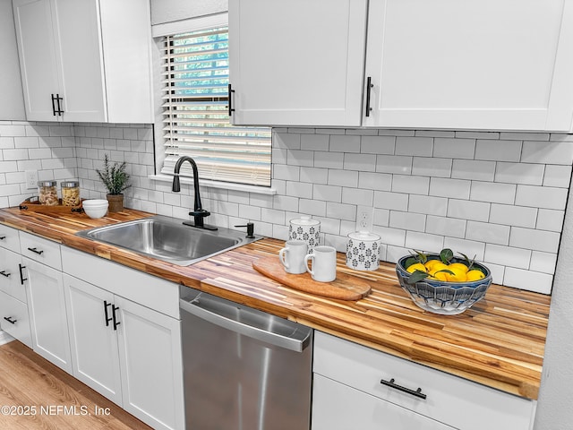 kitchen with wooden counters, dishwasher, sink, and white cabinets