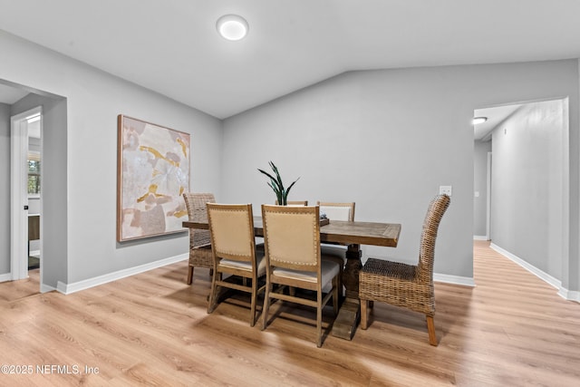 dining room featuring vaulted ceiling and light hardwood / wood-style flooring