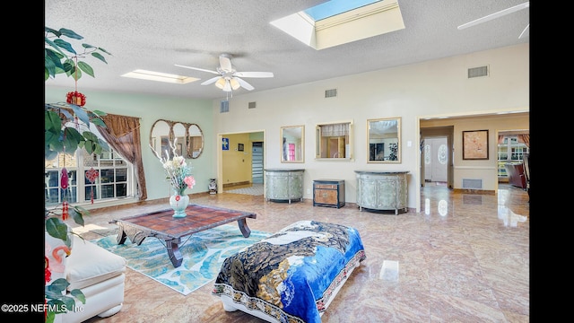 living room featuring vaulted ceiling with skylight, a textured ceiling, and ceiling fan