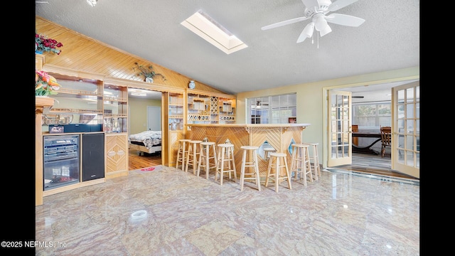 kitchen with lofted ceiling, ceiling fan, a textured ceiling, and a kitchen bar