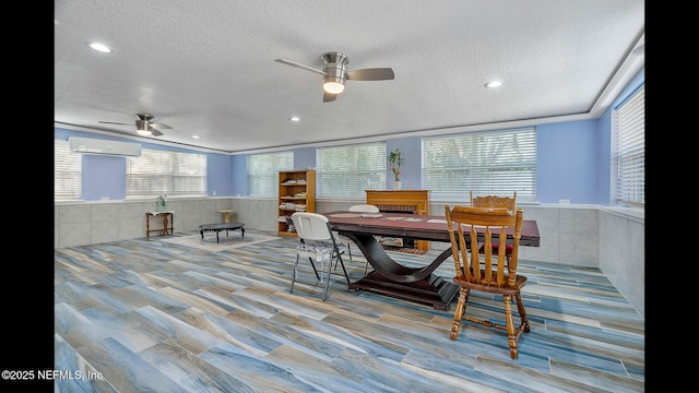 dining room featuring plenty of natural light, a wall mounted air conditioner, and a textured ceiling