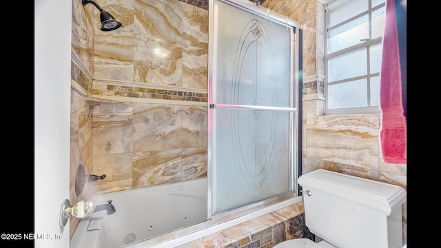 bathroom featuring bath / shower combo with glass door, tile walls, and toilet