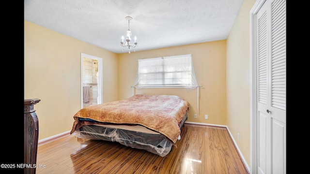 bedroom with a chandelier, a textured ceiling, light wood-type flooring, and a closet