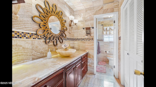 bathroom with vanity, tile walls, and toilet