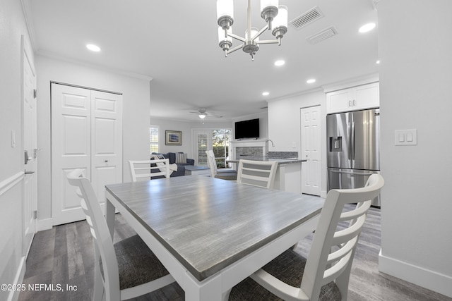 dining area featuring crown molding, dark wood-type flooring, and ceiling fan with notable chandelier