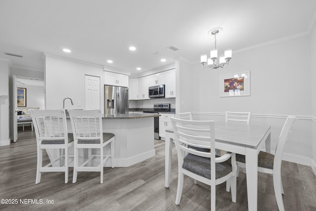 kitchen featuring white cabinetry, light wood-type flooring, dark stone countertops, appliances with stainless steel finishes, and pendant lighting