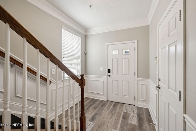 entryway featuring ornamental molding, a textured ceiling, and light hardwood / wood-style flooring