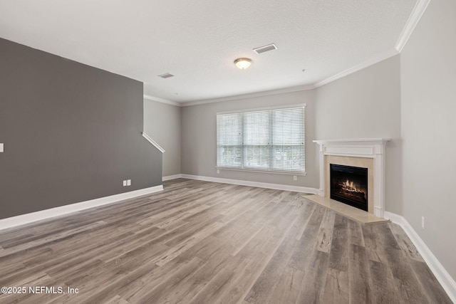 unfurnished living room featuring a premium fireplace, hardwood / wood-style floors, a textured ceiling, and crown molding