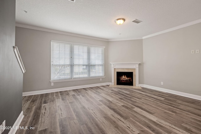 unfurnished living room with hardwood / wood-style flooring, ornamental molding, a premium fireplace, and a textured ceiling