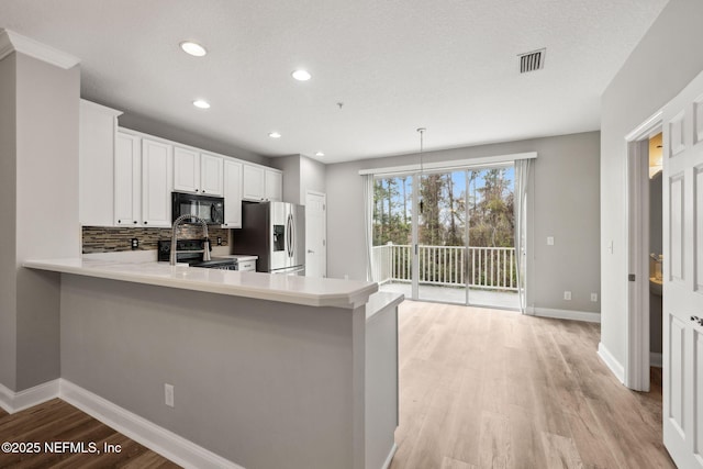 kitchen with white cabinetry, stainless steel fridge with ice dispenser, hanging light fixtures, electric range oven, and kitchen peninsula