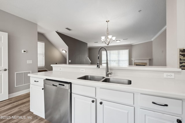 kitchen featuring pendant lighting, stainless steel dishwasher, sink, and white cabinets