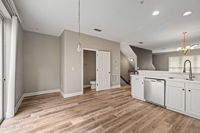 kitchen featuring sink, light hardwood / wood-style flooring, hanging light fixtures, white cabinets, and stainless steel dishwasher