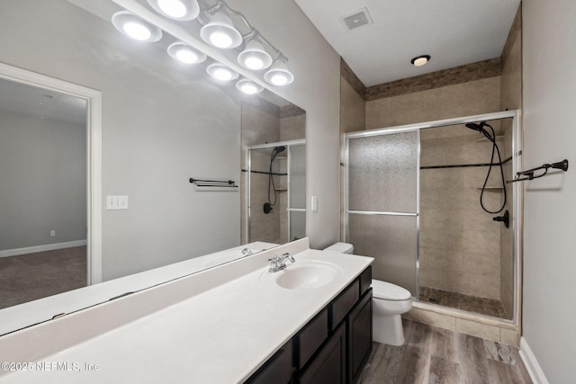 bathroom featuring vanity, a shower with shower door, toilet, and wood-type flooring