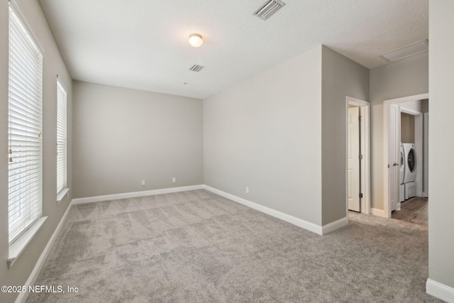 carpeted empty room featuring washer and dryer and a textured ceiling