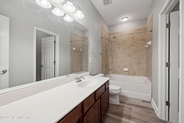 full bathroom with vanity, tiled shower / bath combo, toilet, and hardwood / wood-style flooring