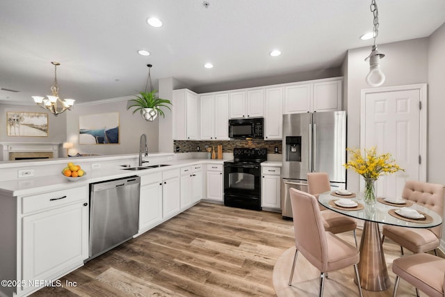 kitchen featuring pendant lighting, sink, black appliances, and white cabinets