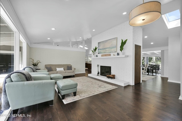 living room with brick wall, dark wood-type flooring, vaulted ceiling with skylight, and a fireplace