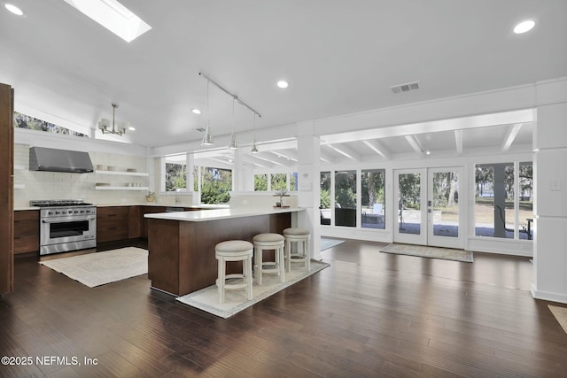 kitchen with french doors, a healthy amount of sunlight, wall chimney exhaust hood, and high end stainless steel range