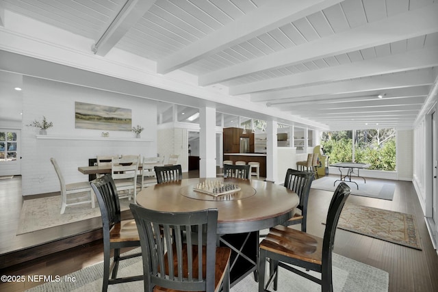 dining room featuring wood-type flooring, beam ceiling, and a wealth of natural light