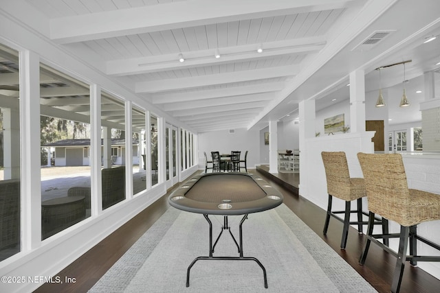 sunroom / solarium featuring beamed ceiling, plenty of natural light, and rail lighting