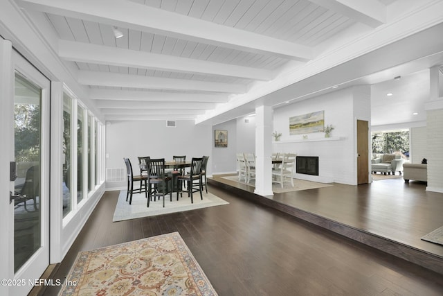 dining room with dark wood-type flooring, wood ceiling, and beamed ceiling