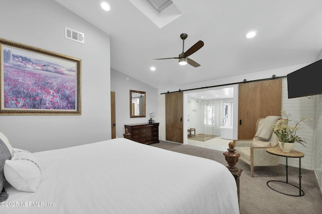 bedroom with vaulted ceiling with skylight, a barn door, light colored carpet, and ceiling fan